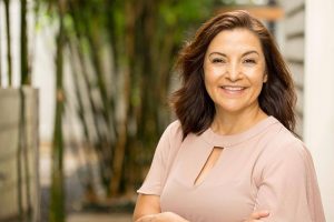 middle-aged woman smiling with her arms crossed outdoors